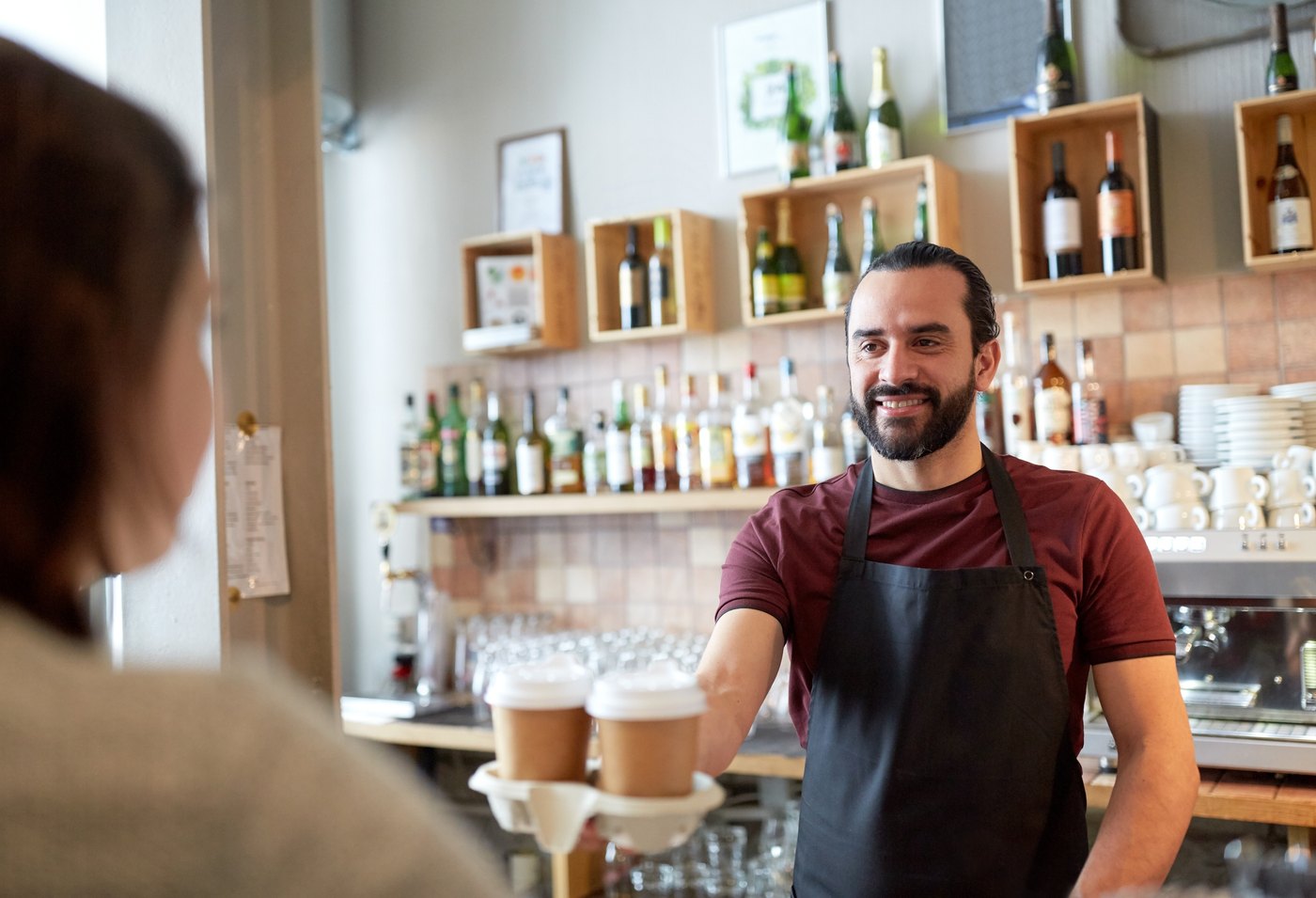 A barista handing over two takeaway coffees at a local Edinburg business